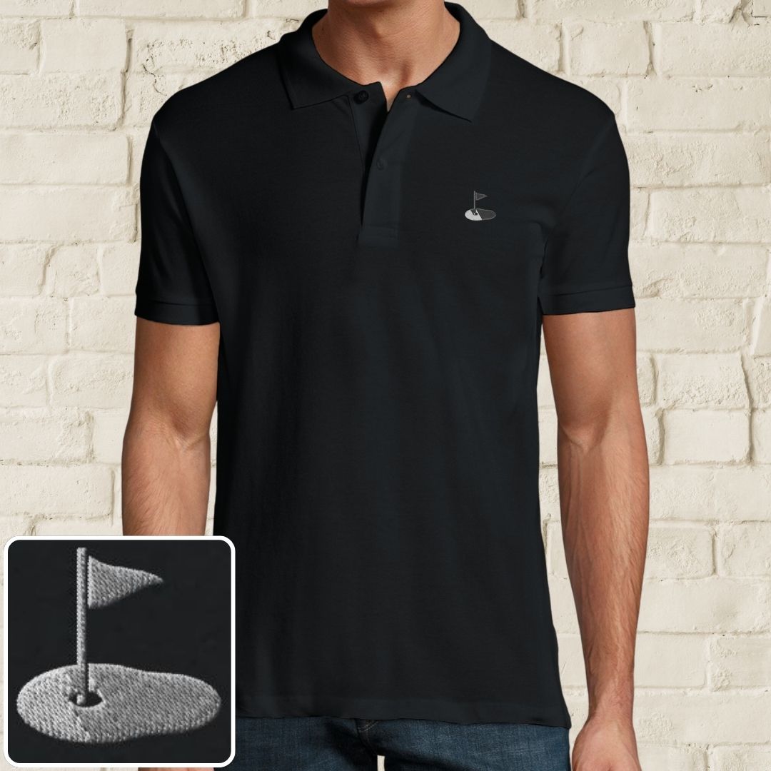 Flag Polo in Black on a light wooden floor lying next to headphones and golf shoes.
