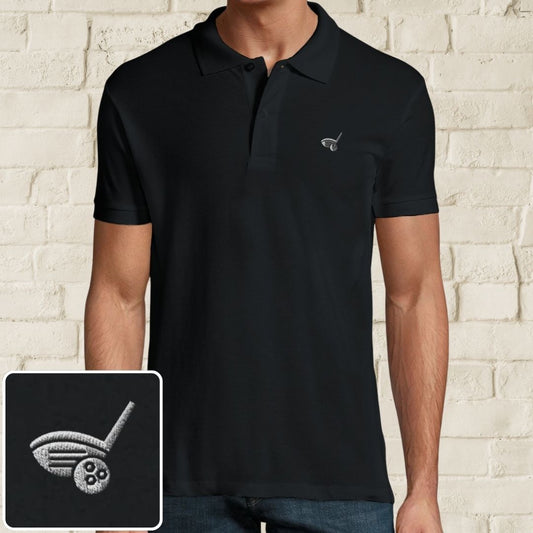 Driver Polo in Black on a light wooden floor lying next to headphones and golf shoes.