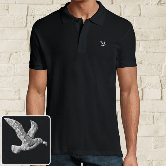Albatross Polo in Black on a light wooden floor lying next to headphones and golf shoes.