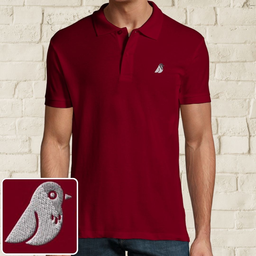 Birdie Polo in Maroon on a light wooden floor lying next to headphones and golf shoes.