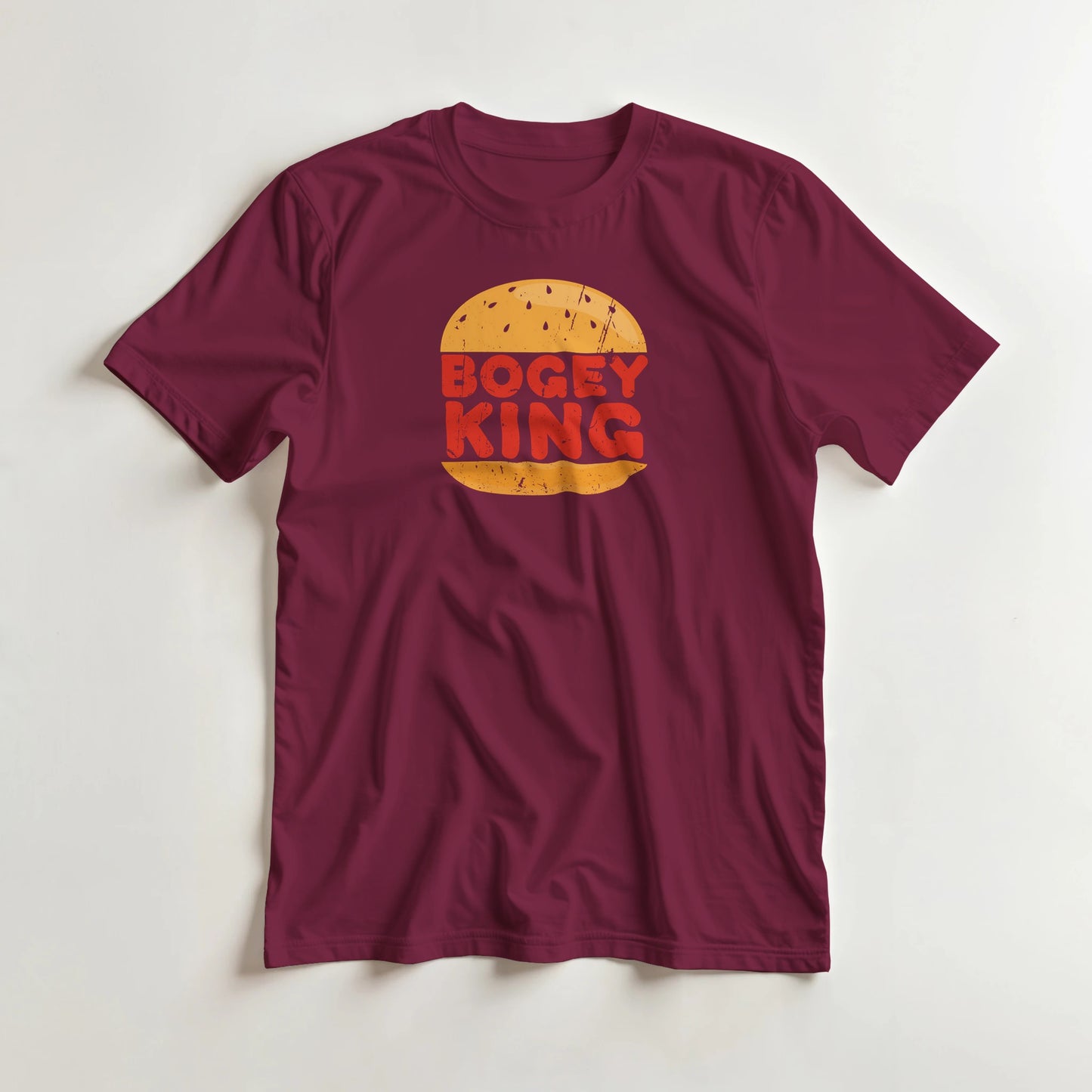 Bogey King T-Shirt in Maroon lying on a plain floor. T-shirt is a unisex cut and 100 per cent cotton.