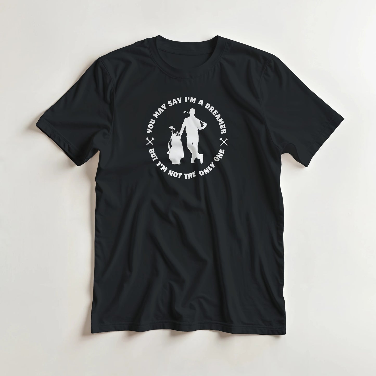You May Say I'm A Dreamer T-Shirt in Black lying on a plain floor. T-shirt is a unisex cut and 100 per cent cotton.