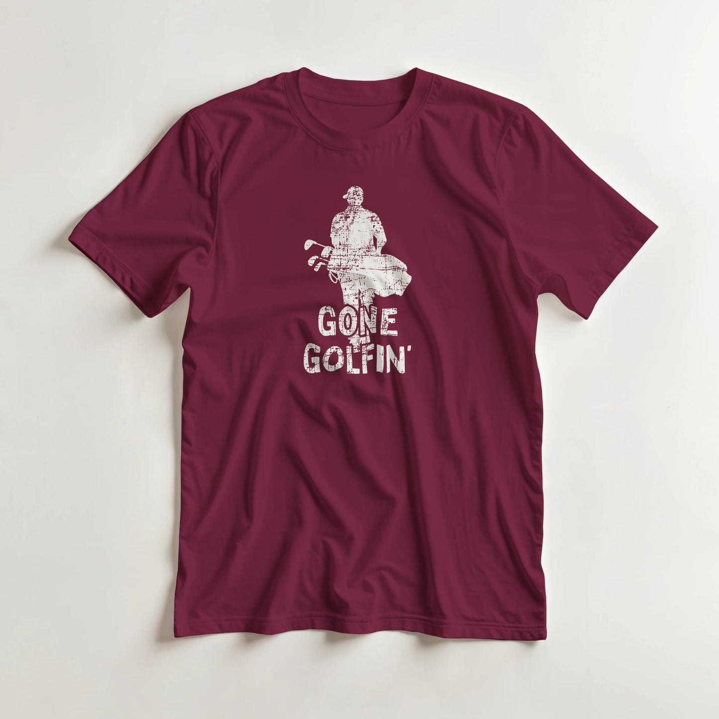 Gone Golfin' T-Shirt in Maroon lying on a plain floor. T-shirt is a unisex cut and 100 per cent cotton.