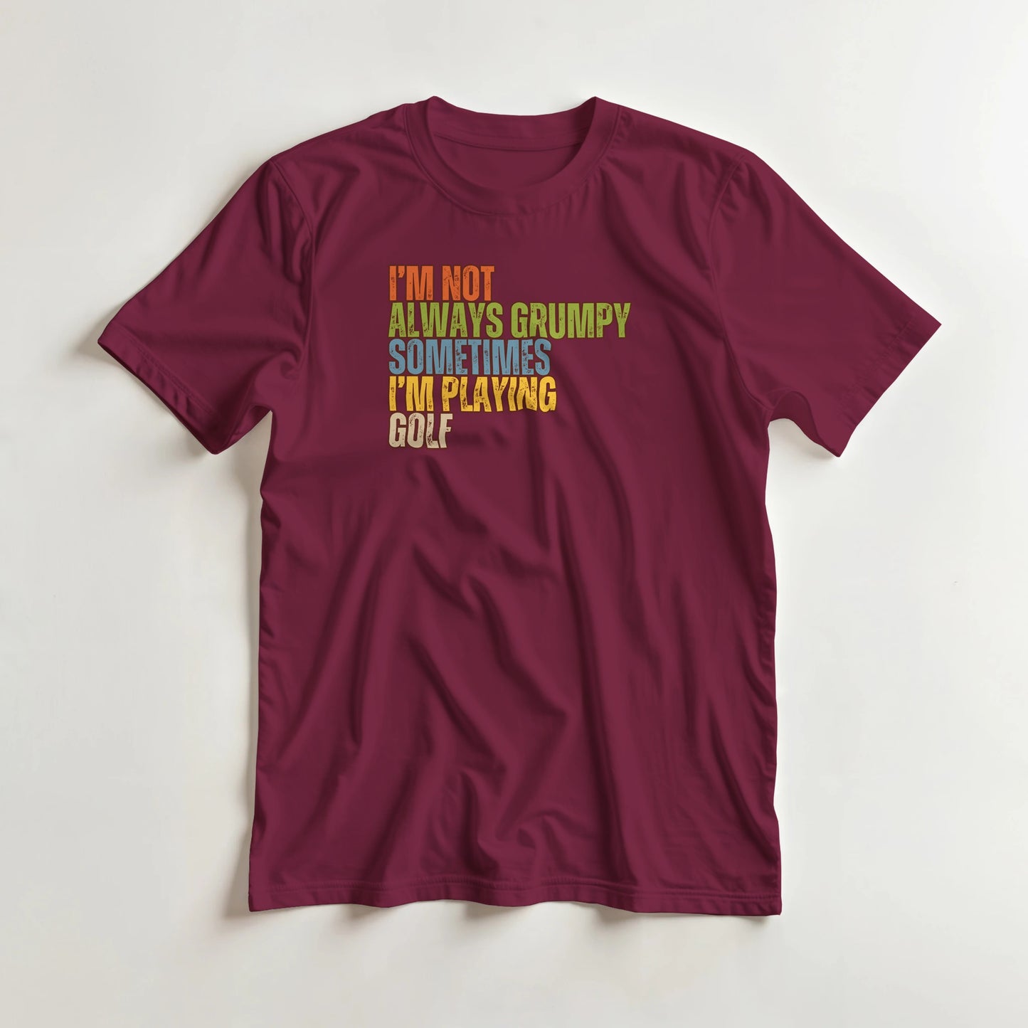Grumpy Classic T-Shirt in Maroon lying on a plain floor. T-shirt is a unisex cut and 100 per cent cotton.
