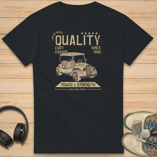 Golf Cart Garage T-Shirt in on a light wooden floor lying next to headphones and golf shoes.