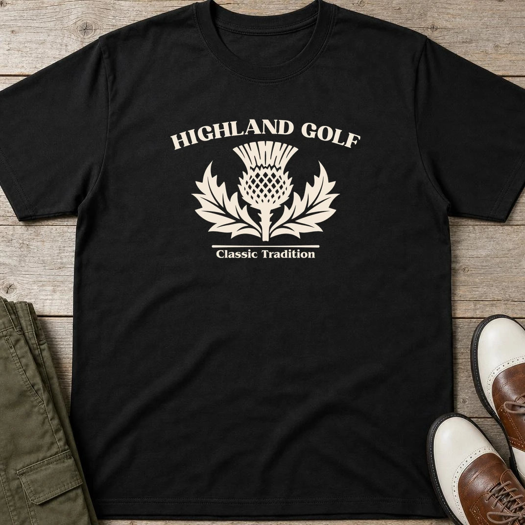 Highland Golf T-Shirt in Black lying on a plain floor. T-shirt is a unisex cut and 100 per cent cotton.