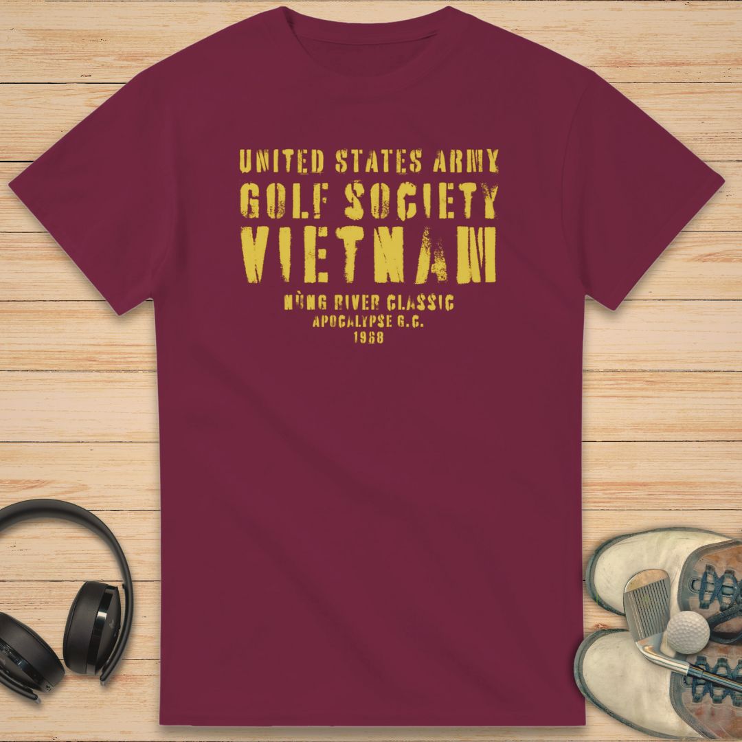 Apocalypse G.C. T-Shirt in Maroon on a light wooden floor lying next to headphones and golf shoes.
