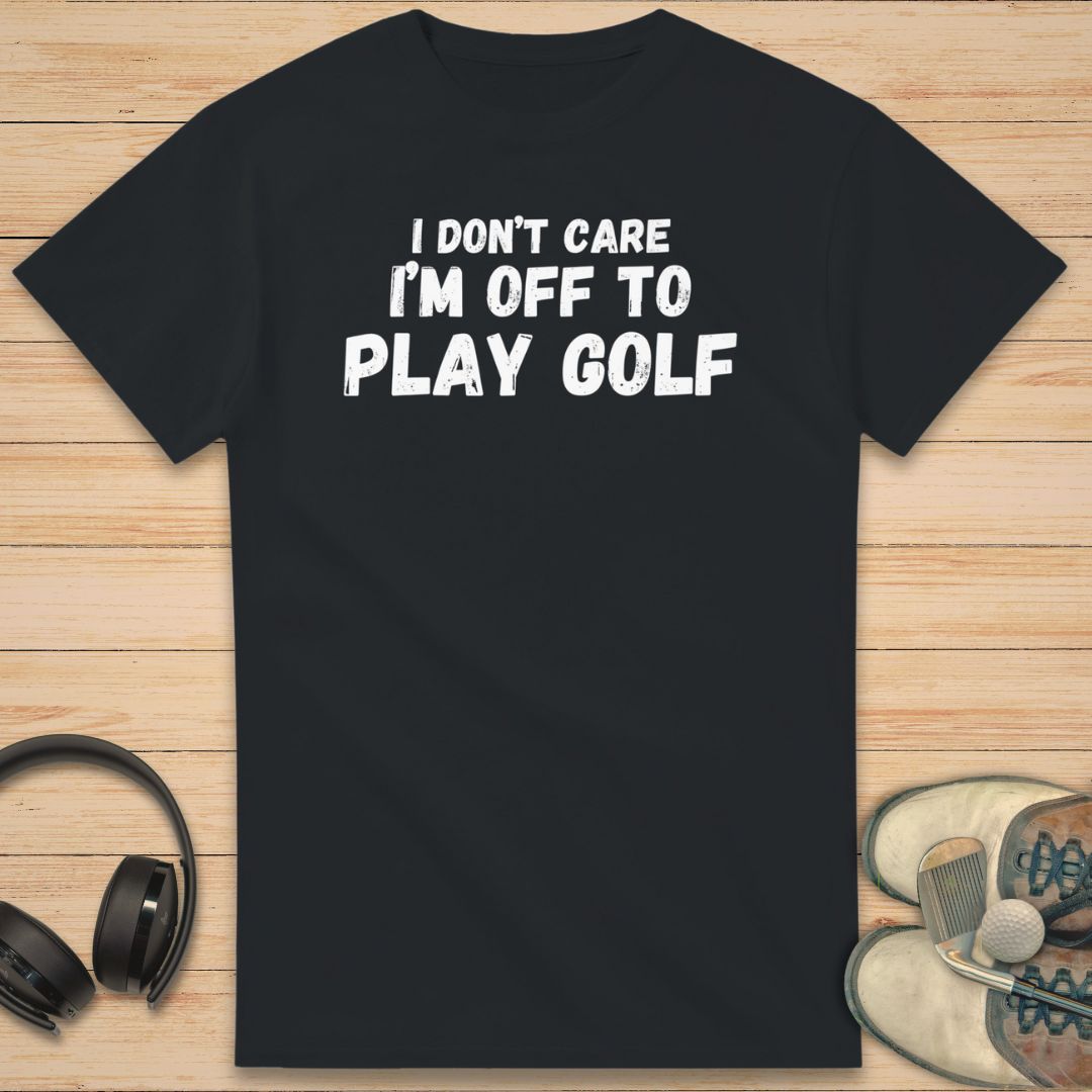 Don't Care T-Shirt in Black on a light wooden floor lying next to headphones and golf shoes.