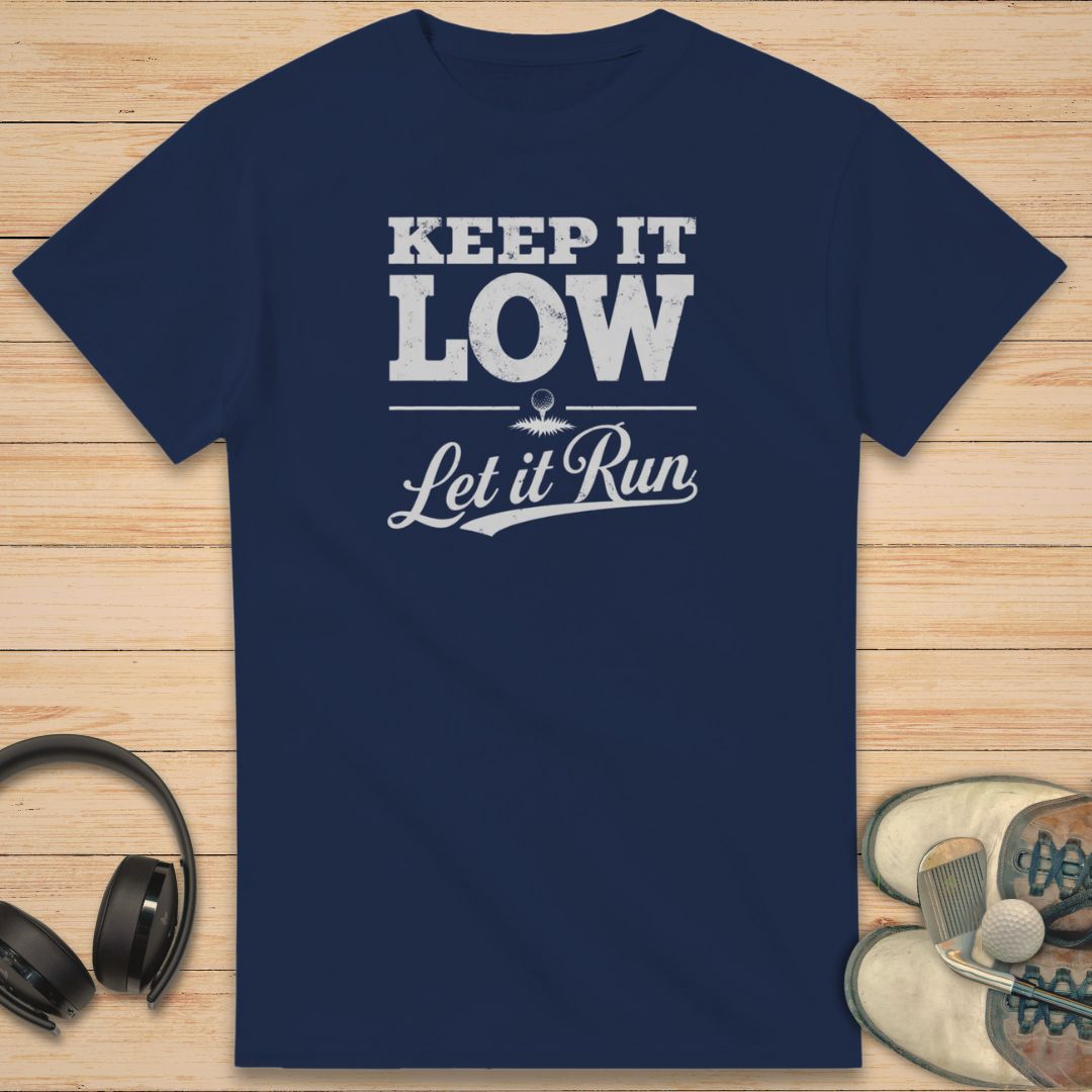 Keep It Low T-Shirt in Navy on a light wooden floor lying next to headphones and golf shoes.