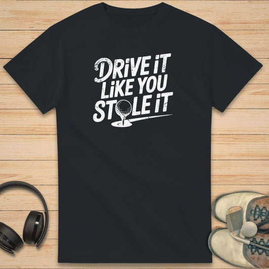Stole It T-Shirt in Black on a light wooden floor lying next to headphones and golf shoes.