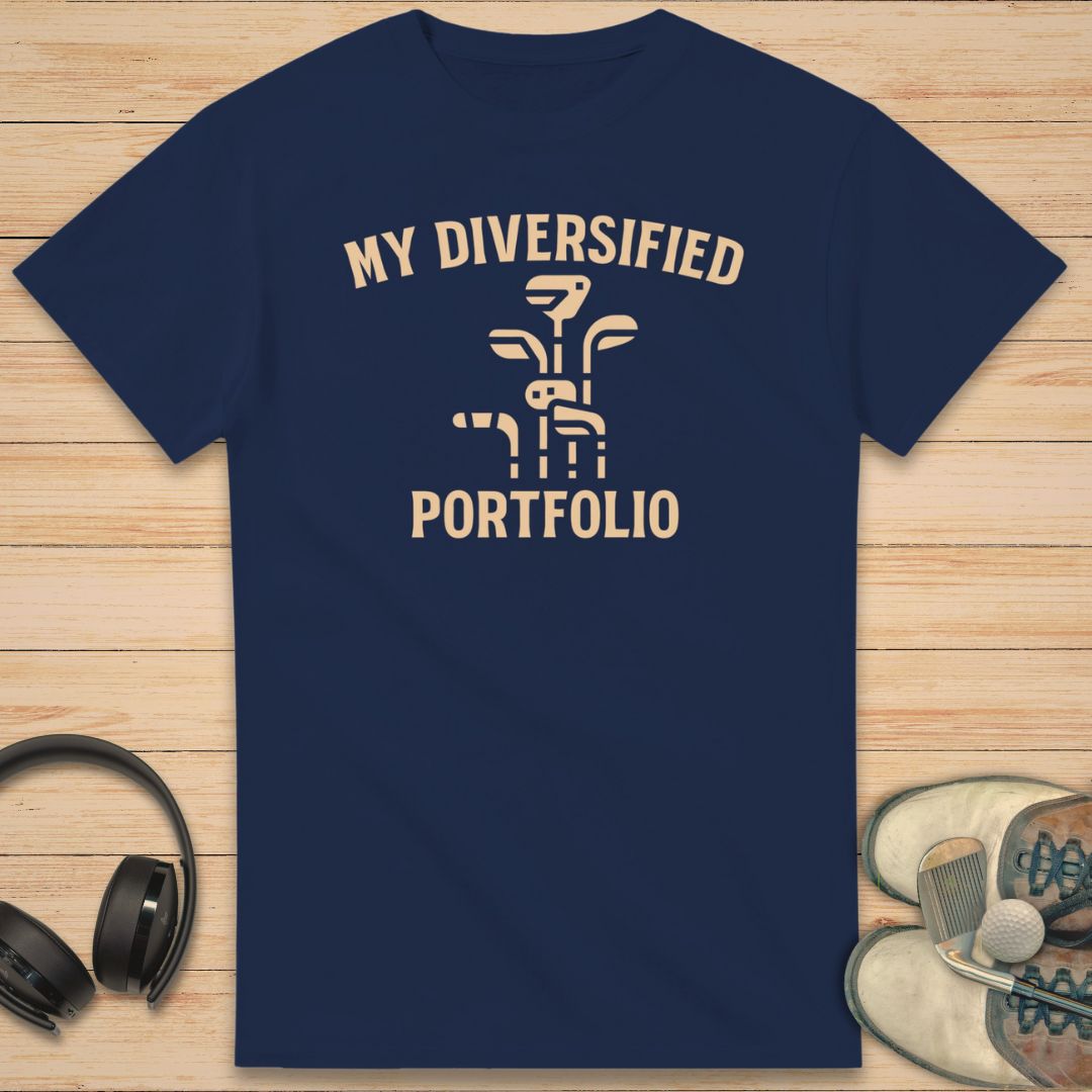 Portfolio T-Shirt in Navy on a light wooden floor lying next to headphones and golf shoes.