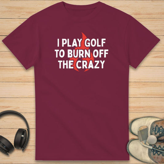 Burn Off T-Shirt in Maroon on a light wooden floor lying next to headphones and golf shoes.