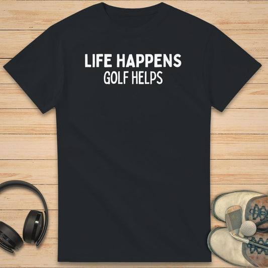 Golf Helps T-Shirt in Black on a light wooden floor lying next to headphones and golf shoes.