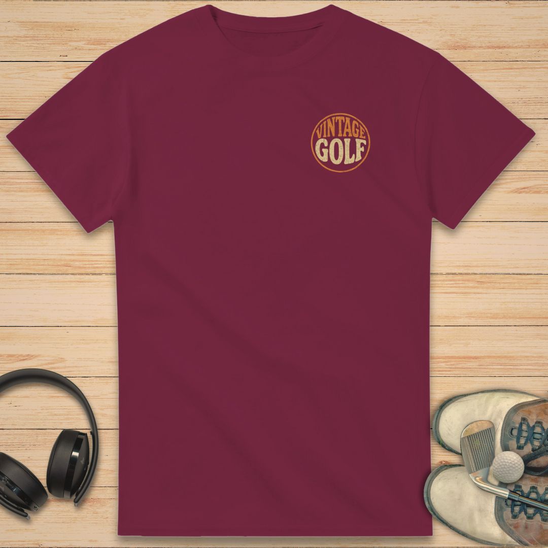 Vintage Golf T-Shirt in Maroon on a light wooden floor lying next to headphones and golf shoes.