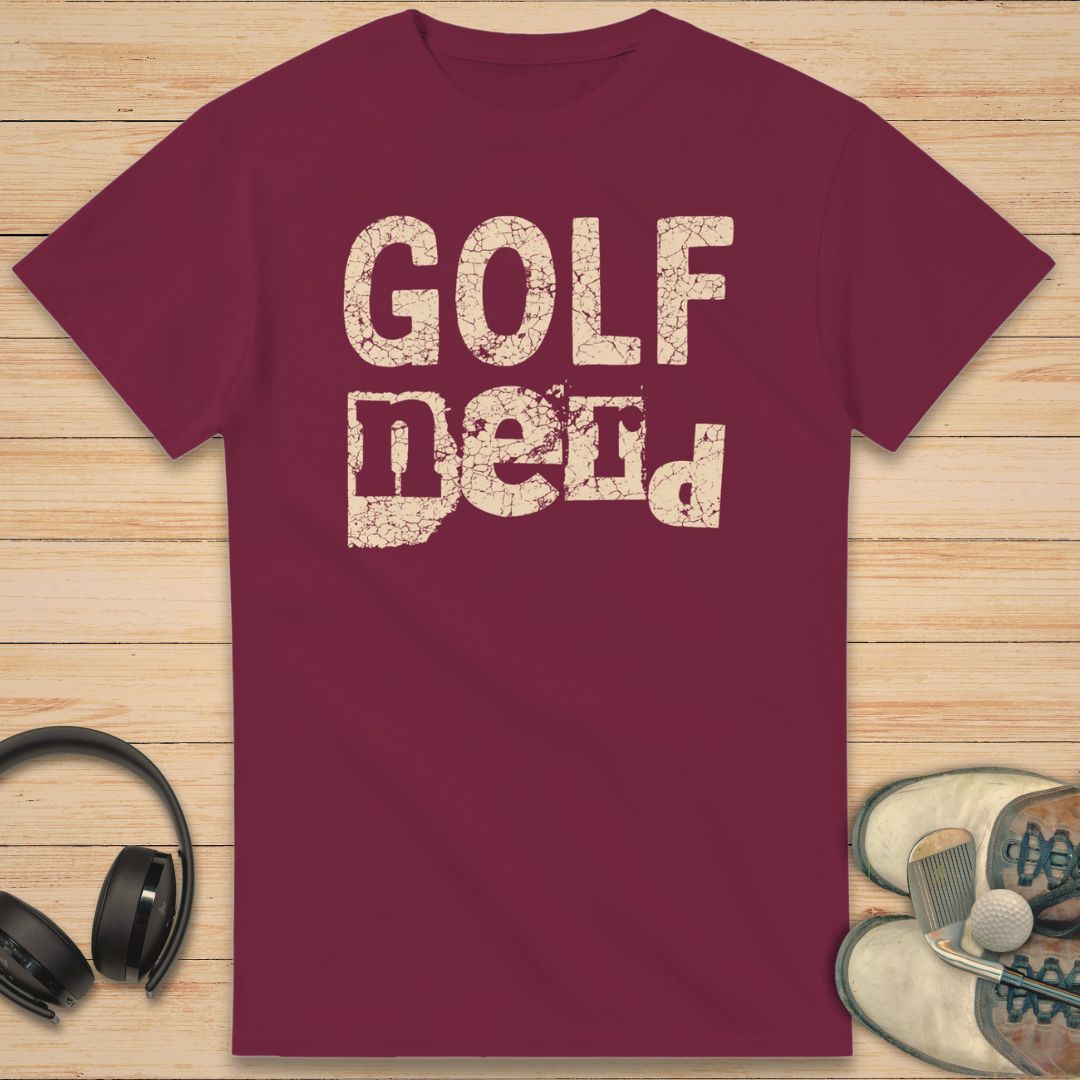 Golf Nerd T-Shirt in Maroon on a light wooden floor lying next to headphones and golf shoes.