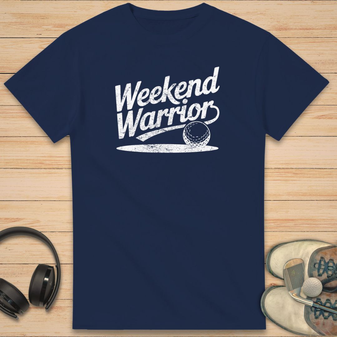 Warrior T-Shirt in Navy on a light wooden floor lying next to headphones and golf shoes.