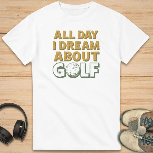 About Golf T-Shirt in White on a light wooden floor lying next to headphones and golf shoes.