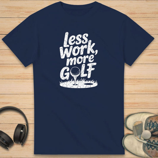 More Golf T-Shirt in Navy on a light wooden floor lying next to headphones and golf shoes.