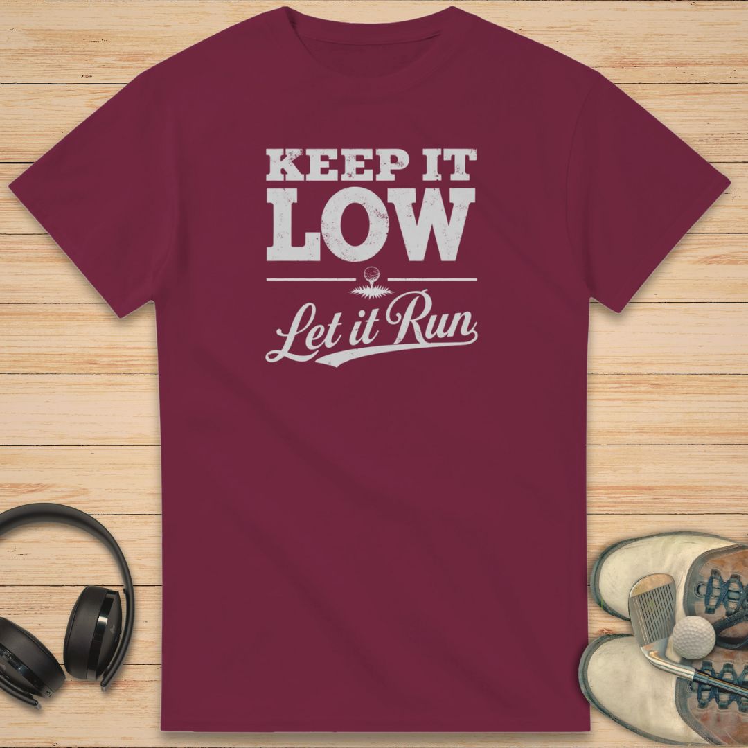 Keep It Low T-Shirt in Maroon on a light wooden floor lying next to headphones and golf shoes.