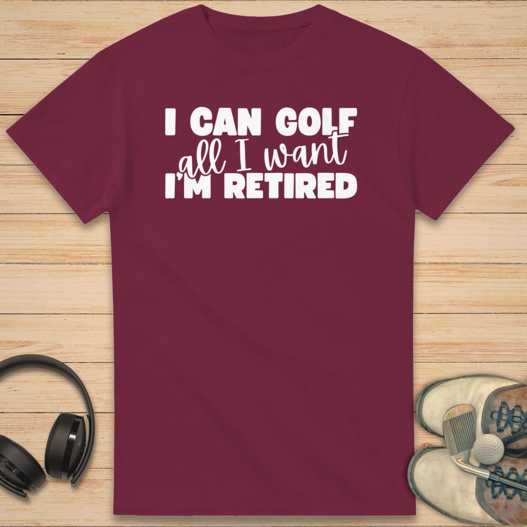 Golf All I Want T-Shirt in Maroon on a light wooden floor lying next to headphones and golf shoes.