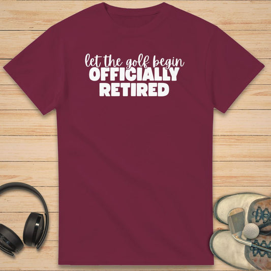 Golf Begin T-Shirt in Maroon on a light wooden floor lying next to headphones and golf shoes.