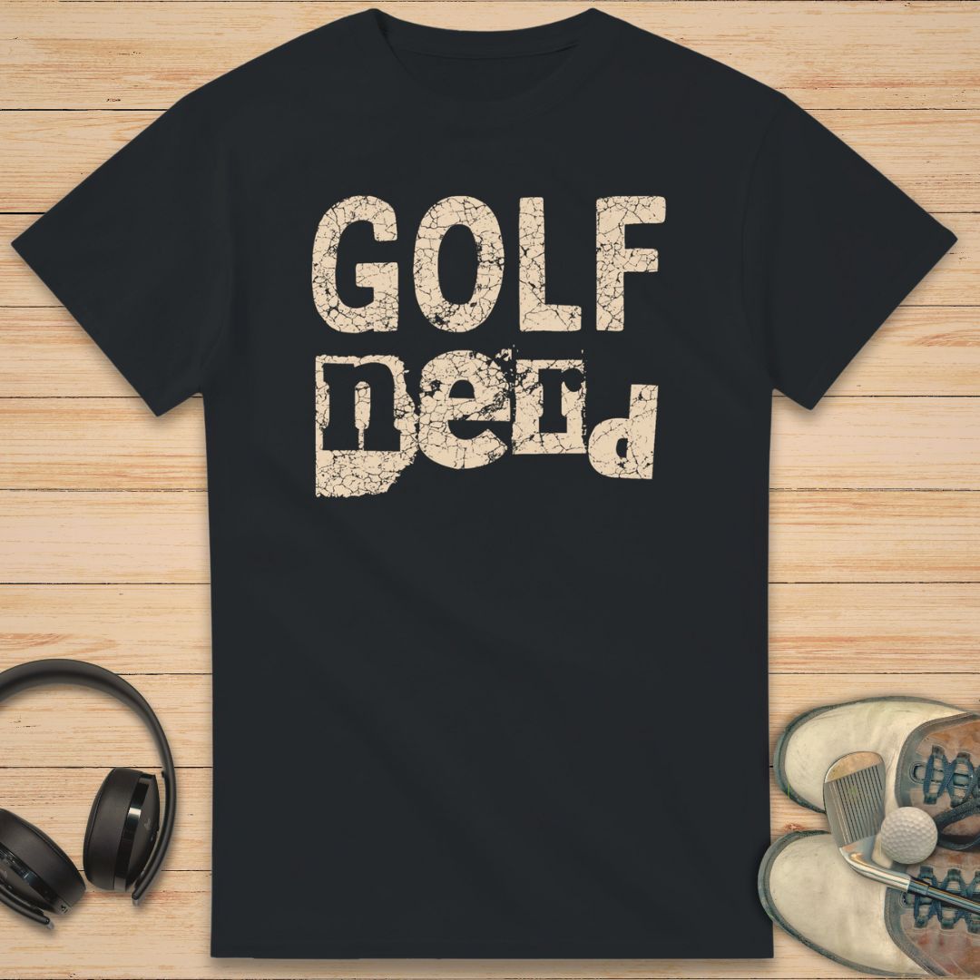 Golf Nerd T-Shirt in Black on a light wooden floor lying next to headphones and golf shoes.