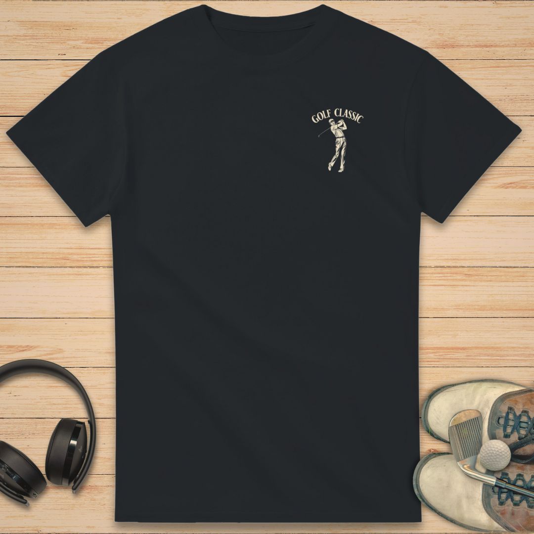 Golf Classic T-Shirt in Black on a light wooden floor lying next to headphones and golf shoes.
