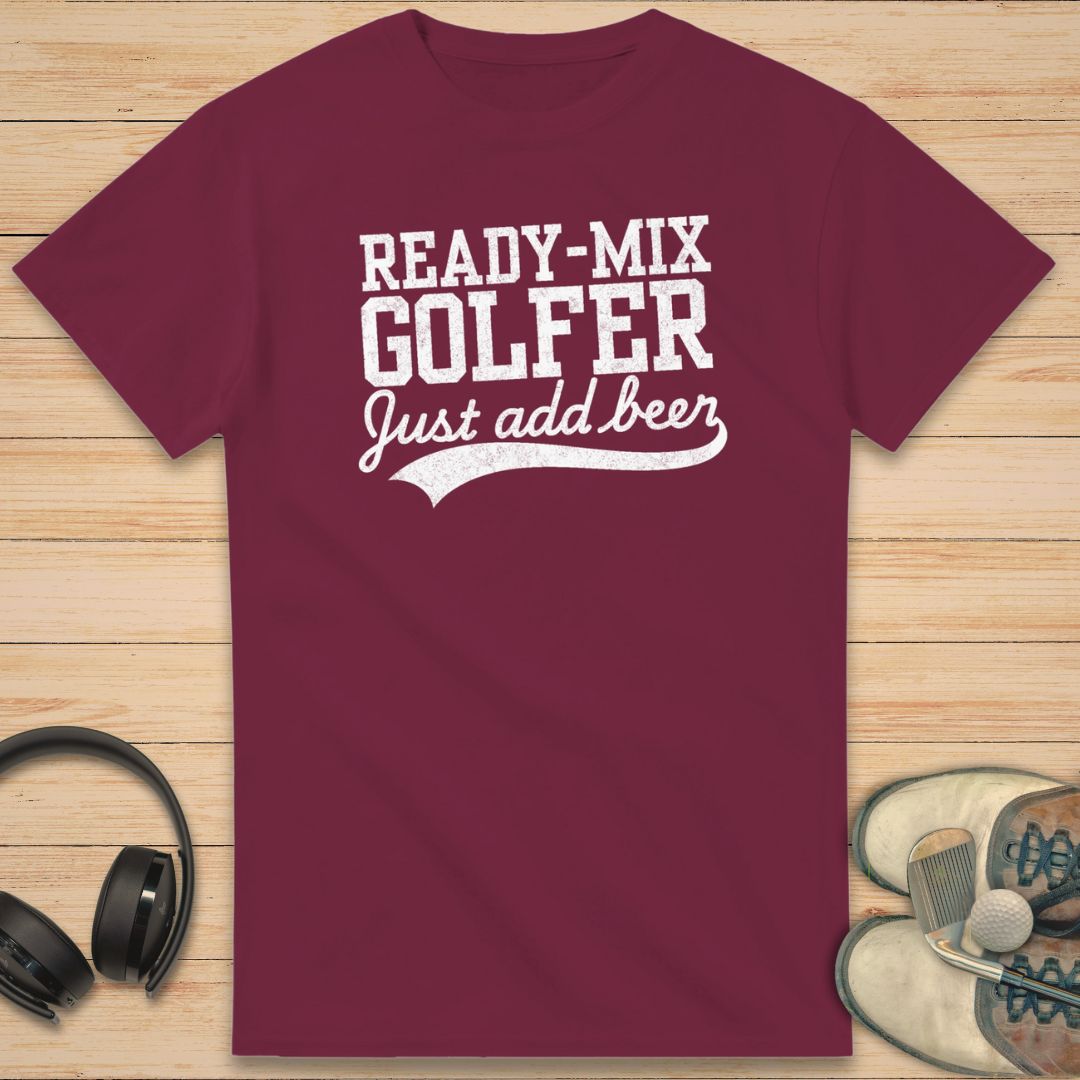 Ready-Mix T-Shirt in Maroon on a light wooden floor lying next to headphones and golf shoes.