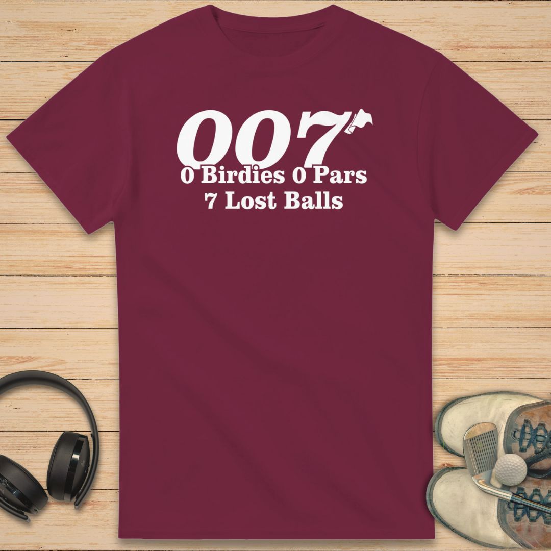 Maroon t-shirt with humorous golf text on a wooden surface with headphones and shoes.