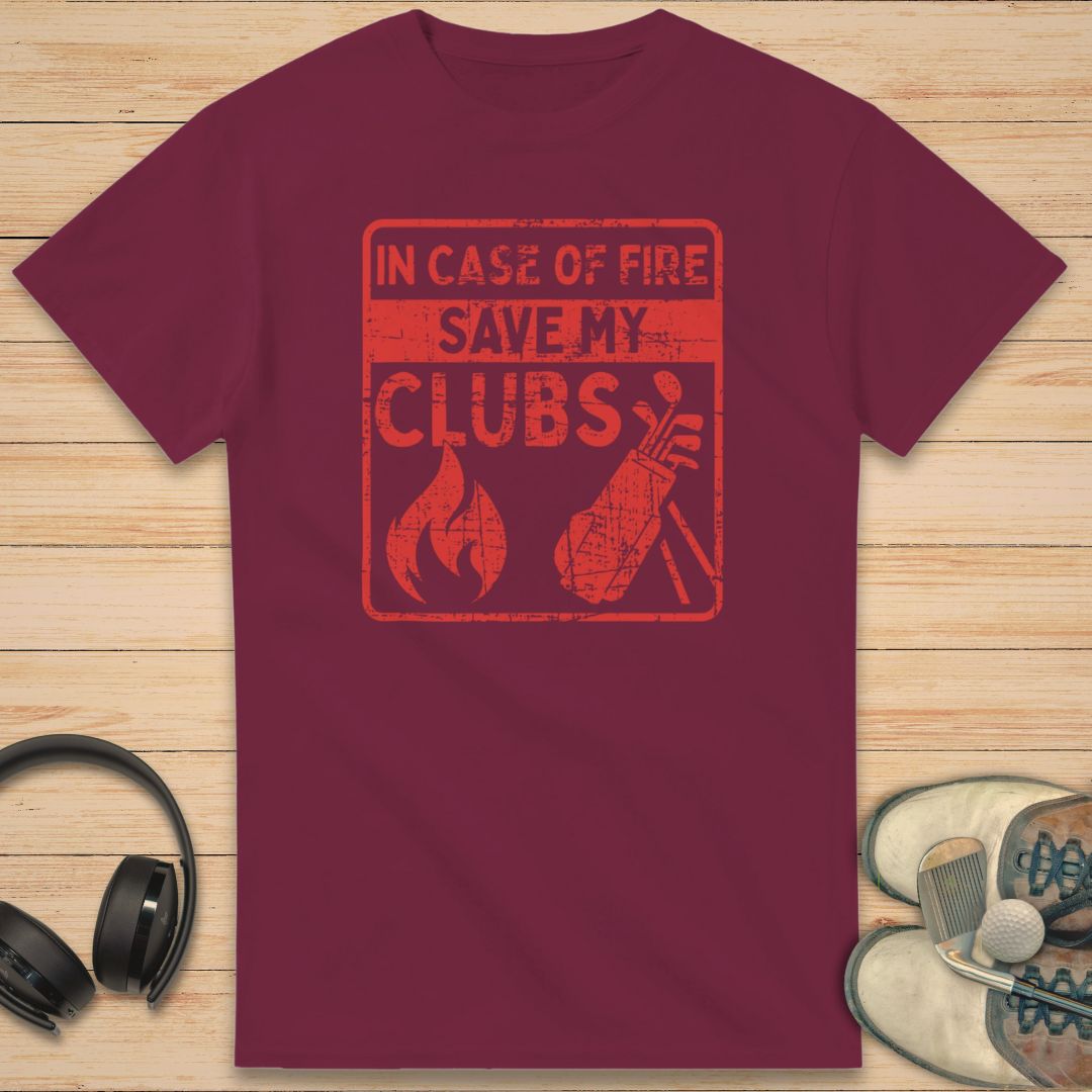Save My Clubs T-Shirt in Maroon on a light wooden floor lying next to headphones and golf shoes.