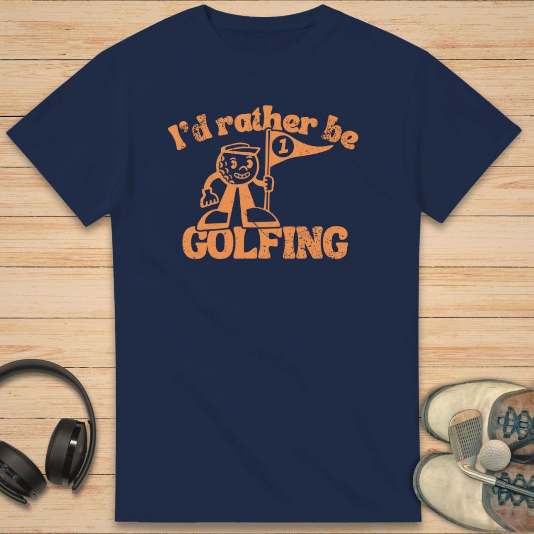 Be Golfing Mascot T-Shirt in Navy on a light wooden floor lying next to headphones and golf shoes.