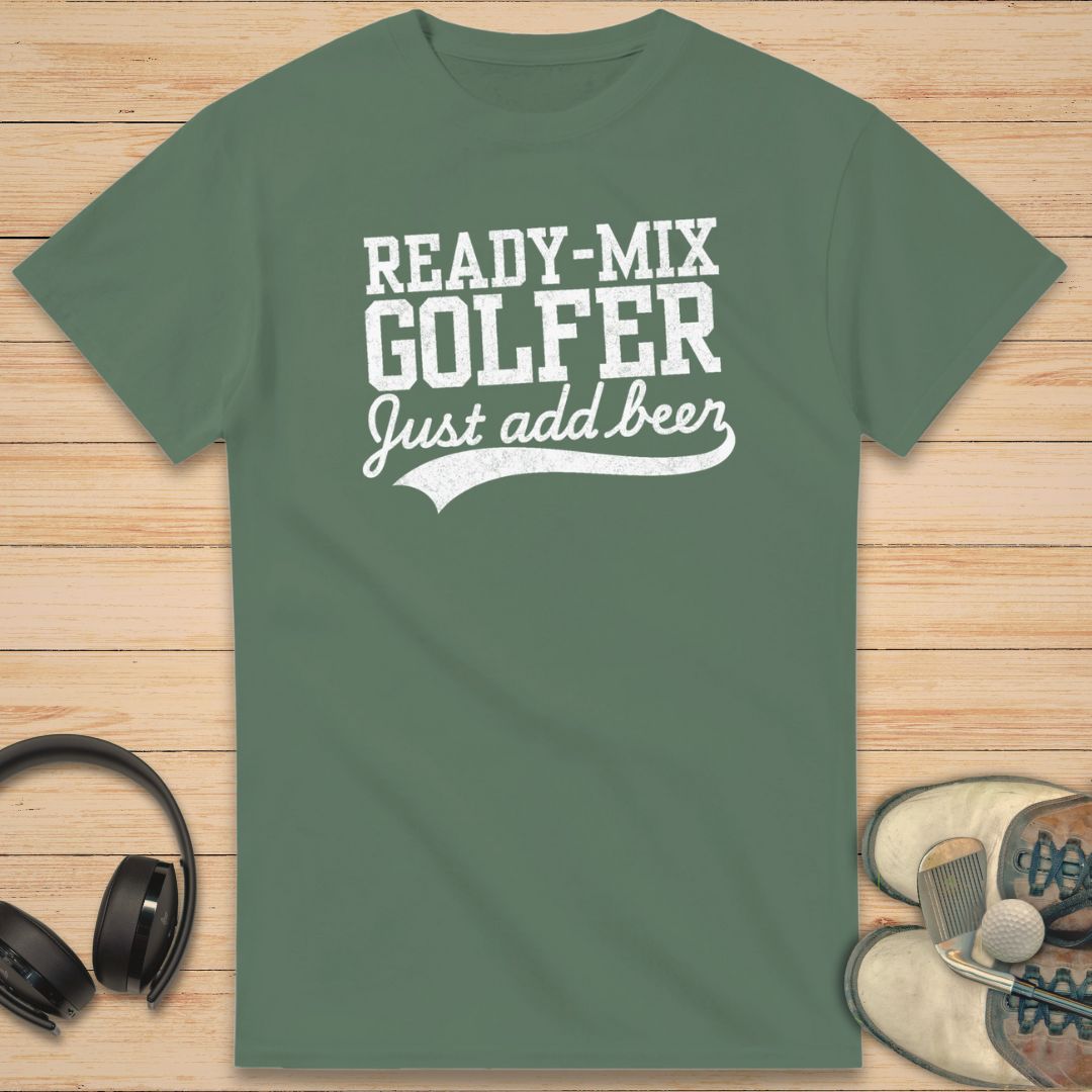 Ready-Mix T-Shirt in Military Green on a light wooden floor lying next to headphones and golf shoes.