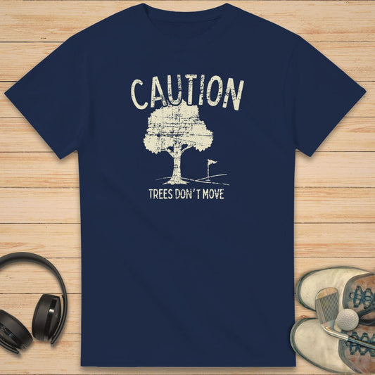 Caution T-Shirt in Navy on a light wooden floor lying next to headphones and golf shoes.
