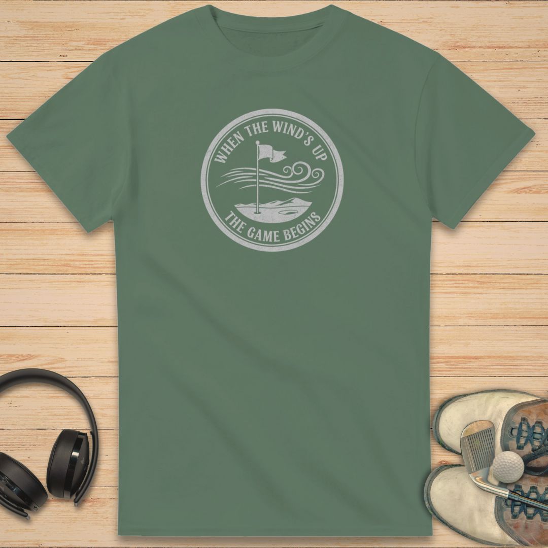 Green t-shirt with a white graphic and text on a wooden surface with headphones and shoes.
