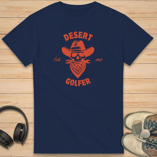 Desert Golfer T-Shirt in Navy on a light wooden floor lying next to headphones and golf shoes.
