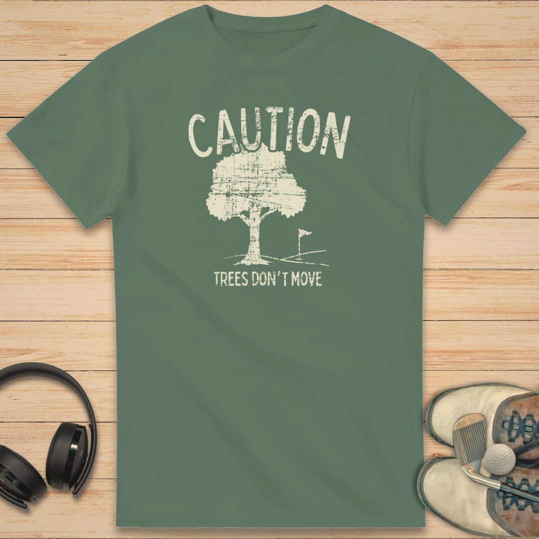 Caution T-Shirt in Military Green on a light wooden floor lying next to headphones and golf shoes.