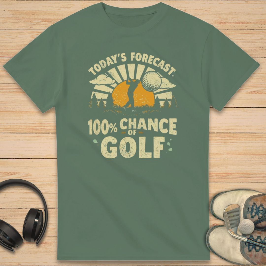 100% Chance of Golf T-Shirt in Military Green on a light wooden floor lying next to headphones and golf shoes.