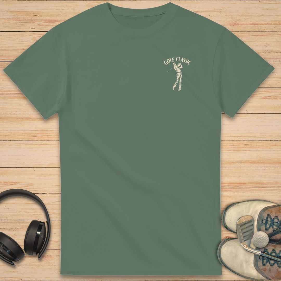 Golf Classic T-Shirt in Military Green on a light wooden floor lying next to headphones and golf shoes.