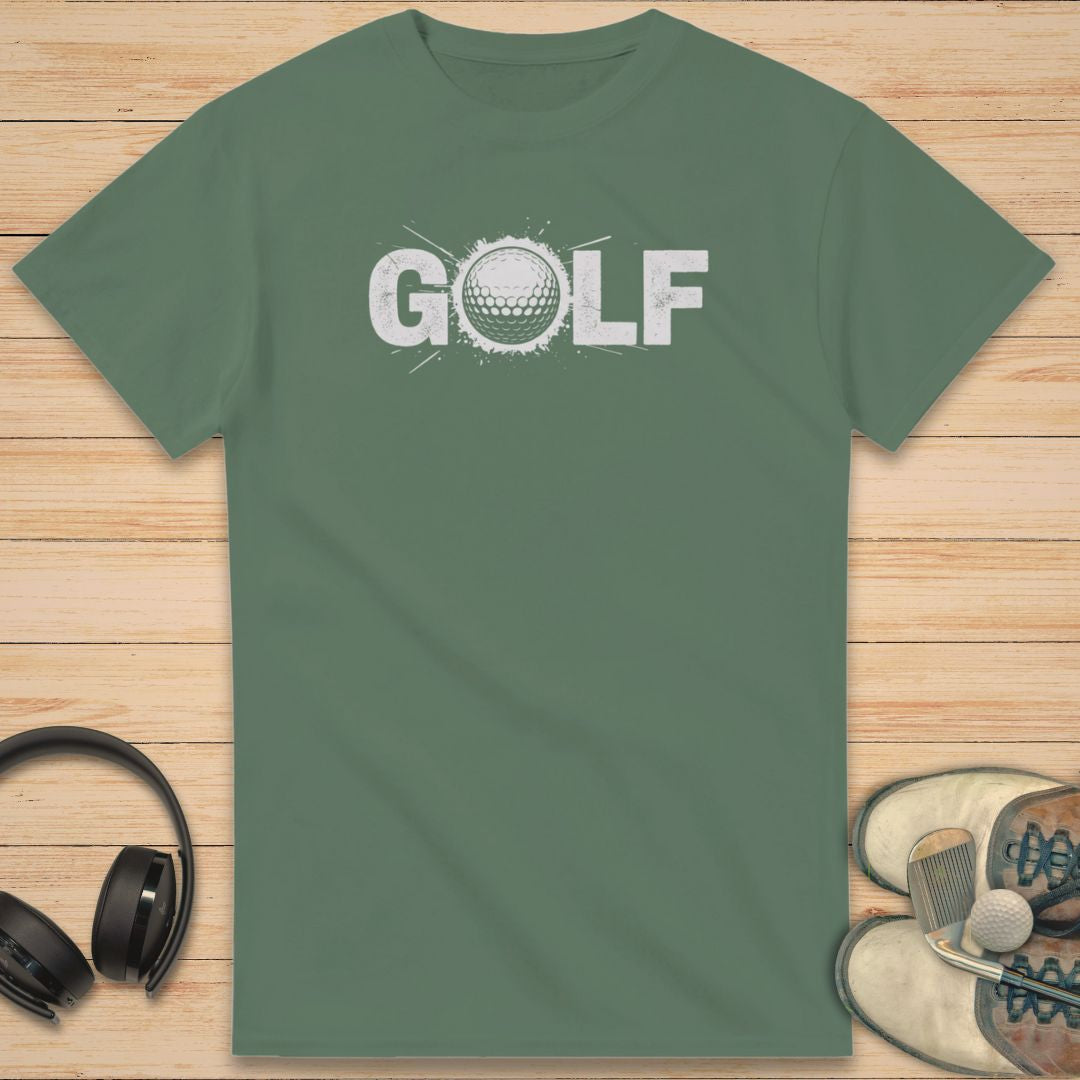Golf Crash T-Shirt in Military Green on a light wooden floor lying next to headphones and golf shoes.
