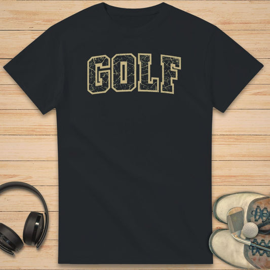 Varsity Golf T-Shirt in Black on a light wooden floor lying next to headphones and golf shoes.
