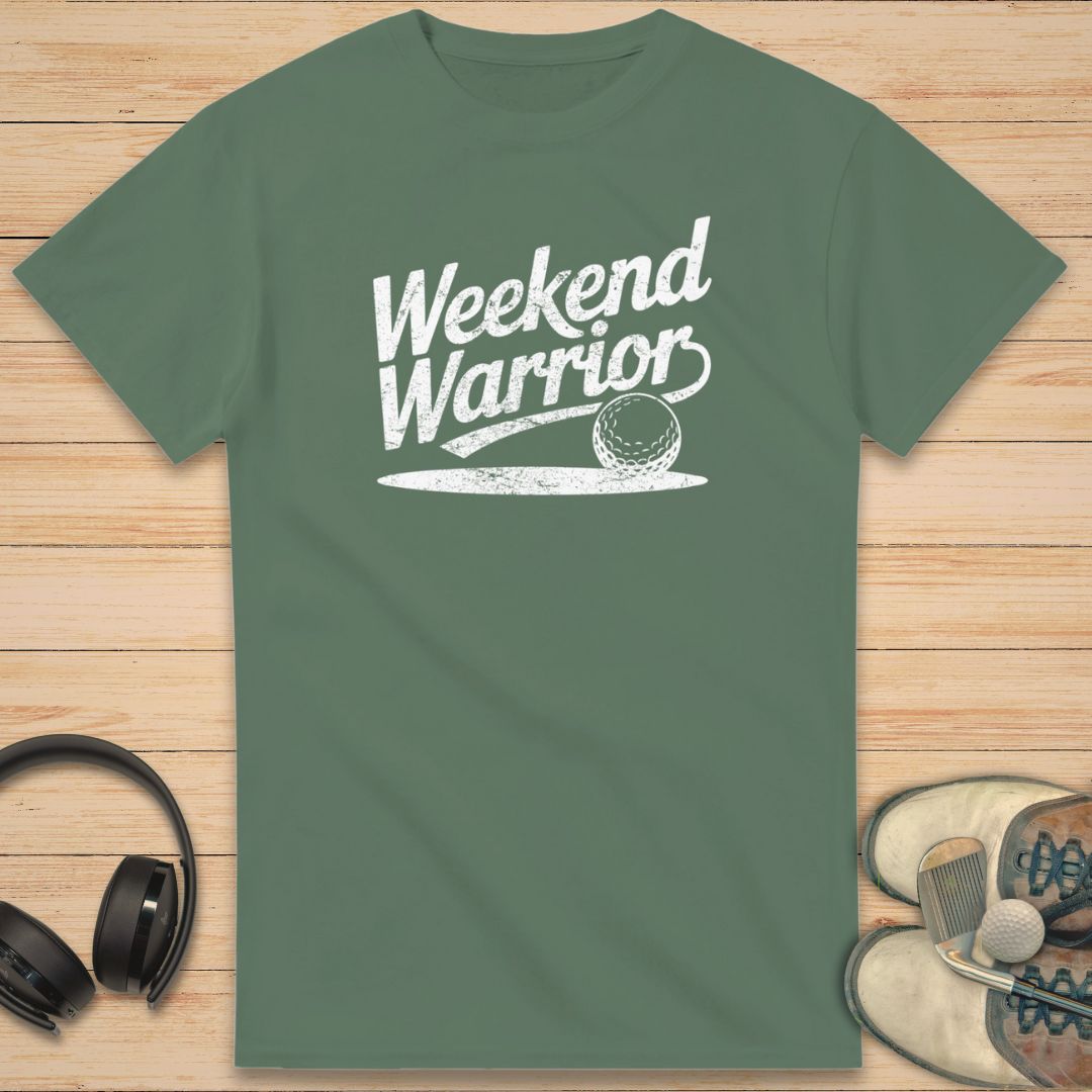Warrior T-Shirt in Military Green on a light wooden floor lying next to headphones and golf shoes.