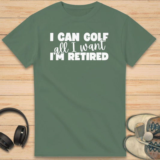 Golf All I Want T-Shirt in Military Green on a light wooden floor lying next to headphones and golf shoes.