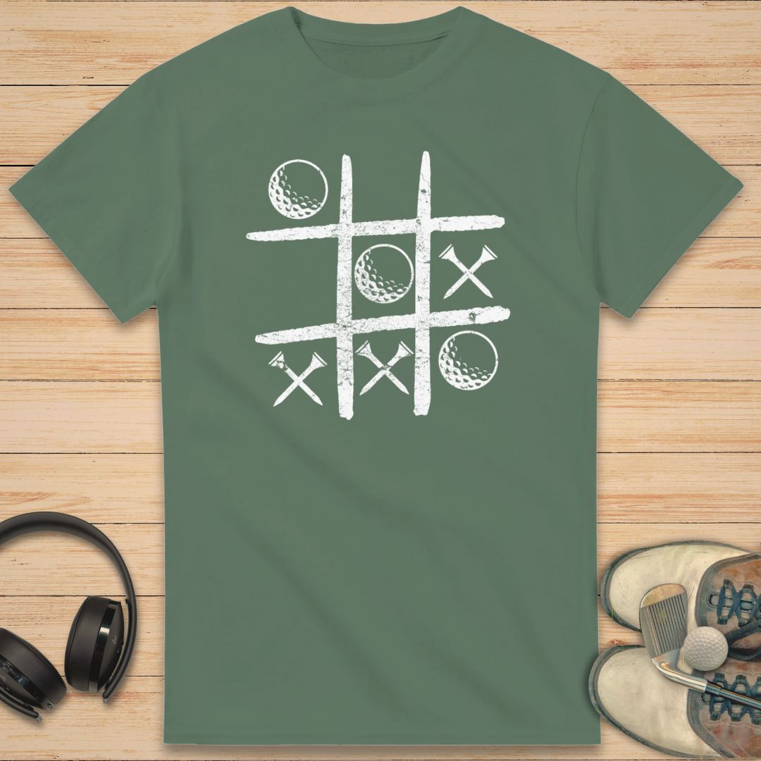 Balls And Tees T-Shirt in Military Green on a light wooden floor lying next to headphones and golf shoes.