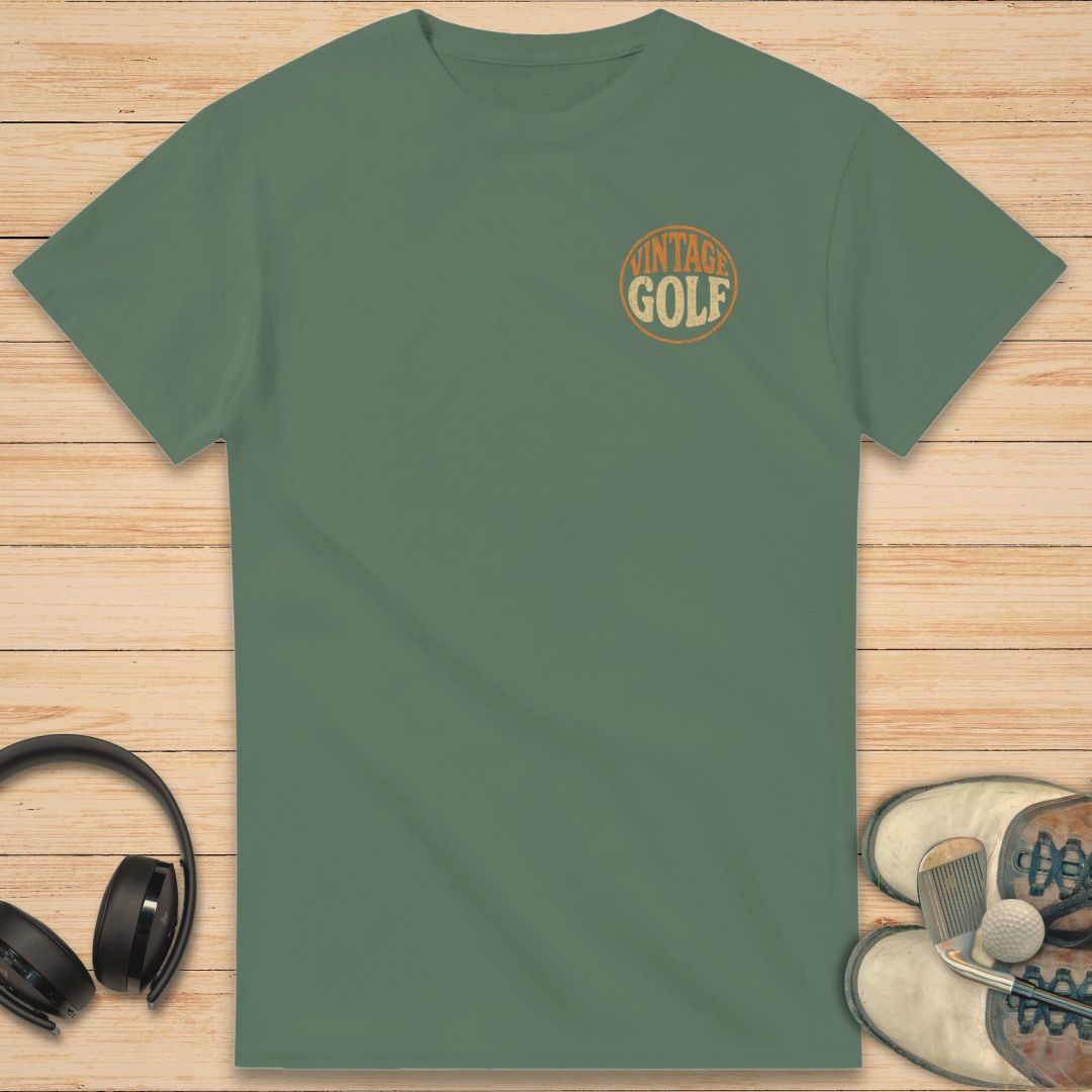 Vintage Golf T-Shirt in Military Green on a light wooden floor lying next to headphones and golf shoes.