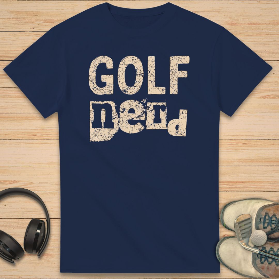 Golf Nerd T-Shirt in Navy on a light wooden floor lying next to headphones and golf shoes.