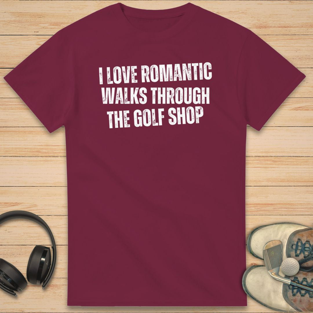 Romantic Walks T-Shirt in Maroon on a light wooden floor lying next to headphones and golf shoes.