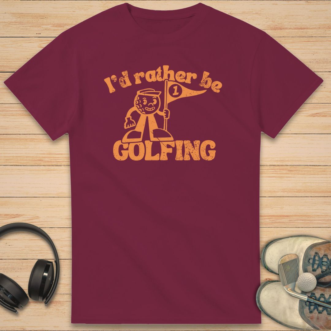 Be Golfing Mascot T-Shirt in Maroon on a light wooden floor lying next to headphones and golf shoes.