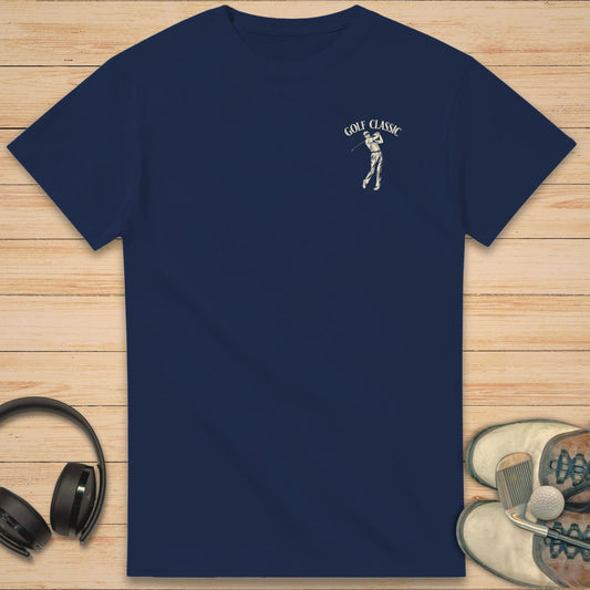 Golf Classic T-Shirt in Navy on a light wooden floor lying next to headphones and golf shoes.