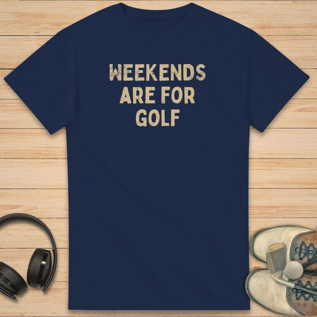 Weekends T-Shirt in Navy on a light wooden floor lying next to headphones and golf shoes.