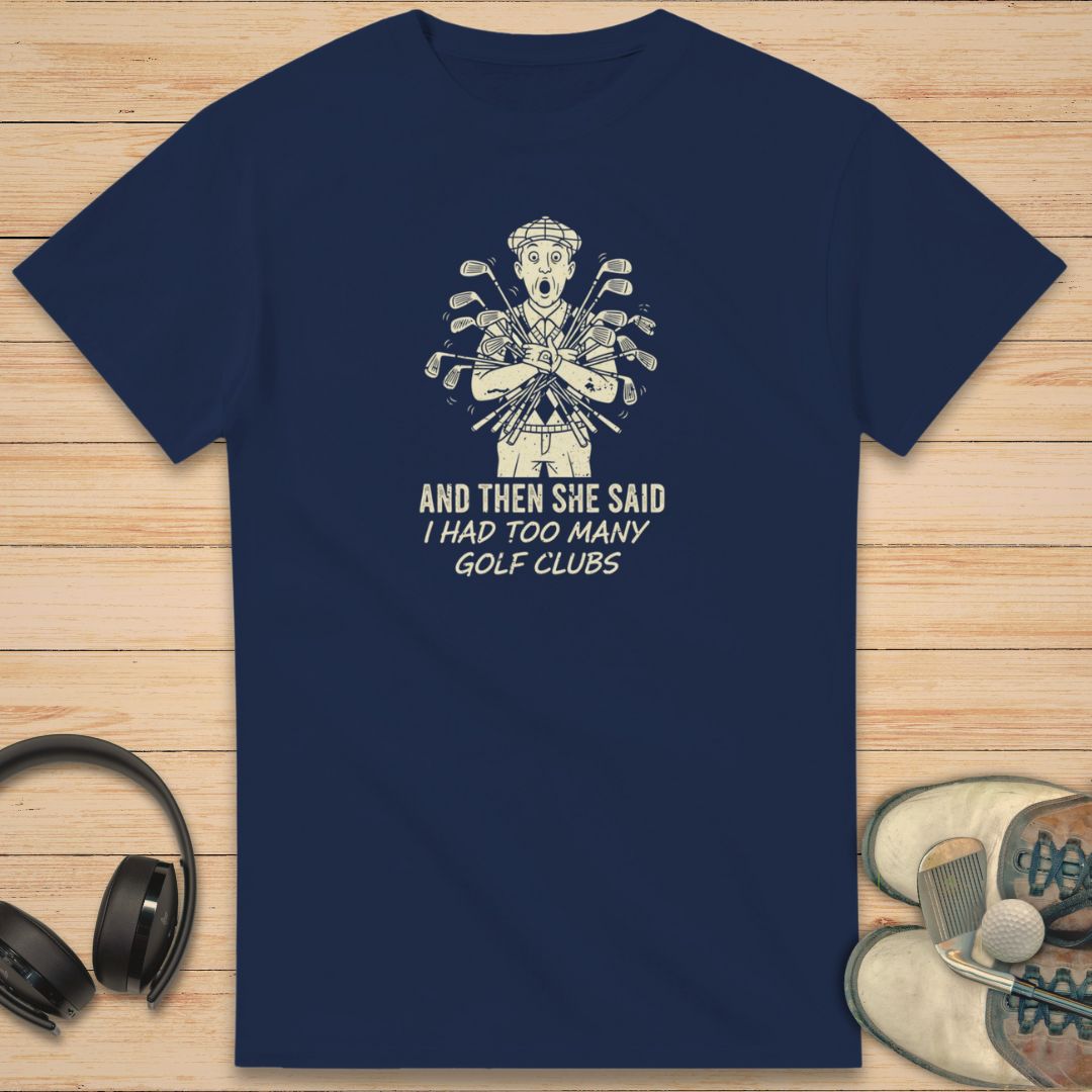 She Said T-Shirt in Navy on a light wooden floor lying next to headphones and golf shoes.